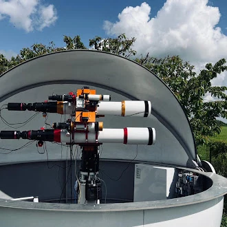 Twin refractors with cameras on one mount in an open observatory dome