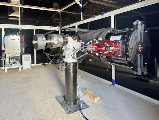 A large observatory telescope with red fittings on a steel pier, in an observatory building
